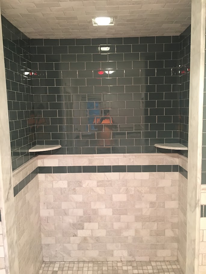Duche com revestimento em azulejos escuros e mármore claro